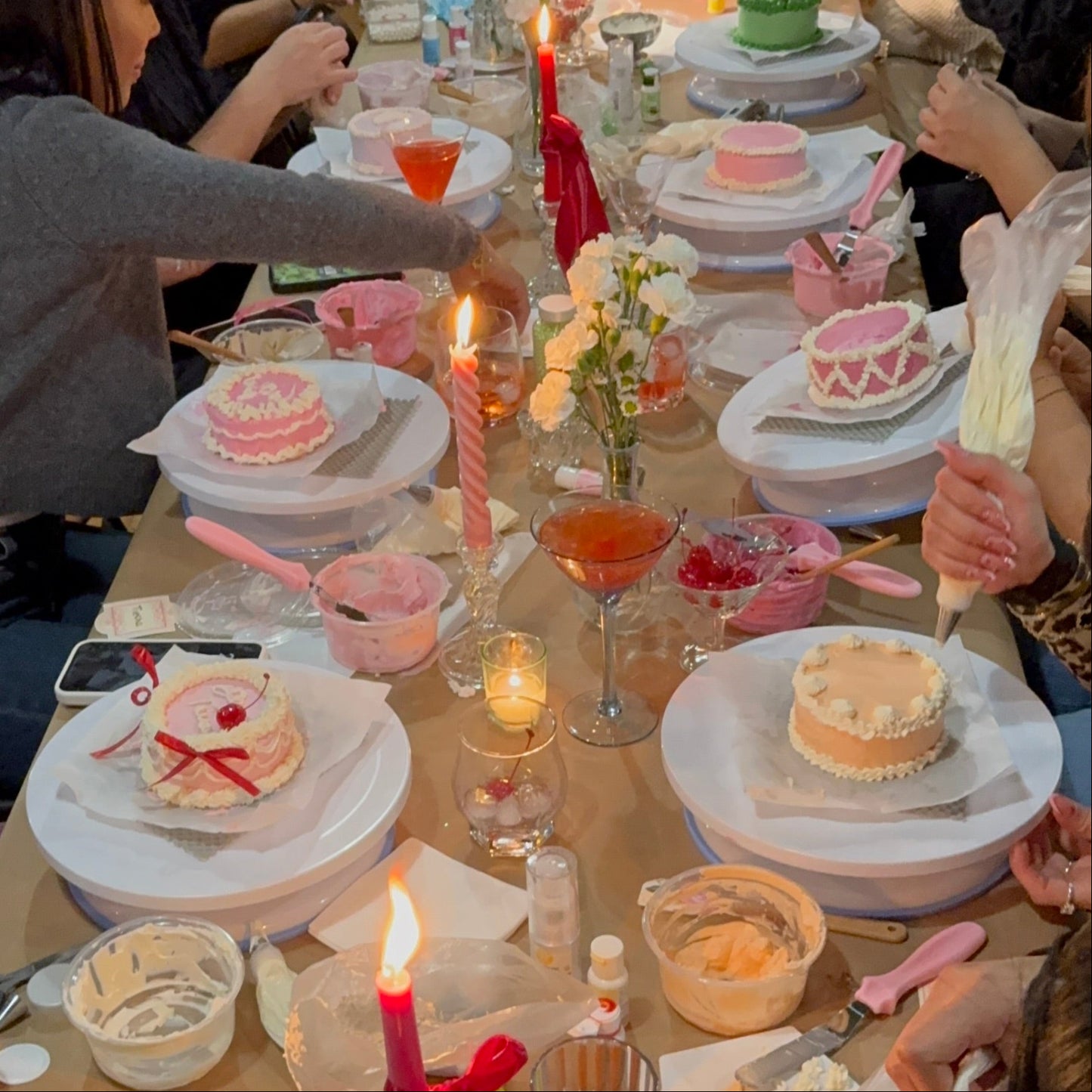 Close-up of guests piping onto a bento cake during a cake decorating class in Montreal