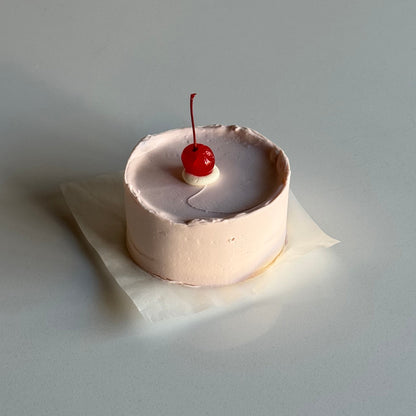 Small cake with a cherry on top on a white surface