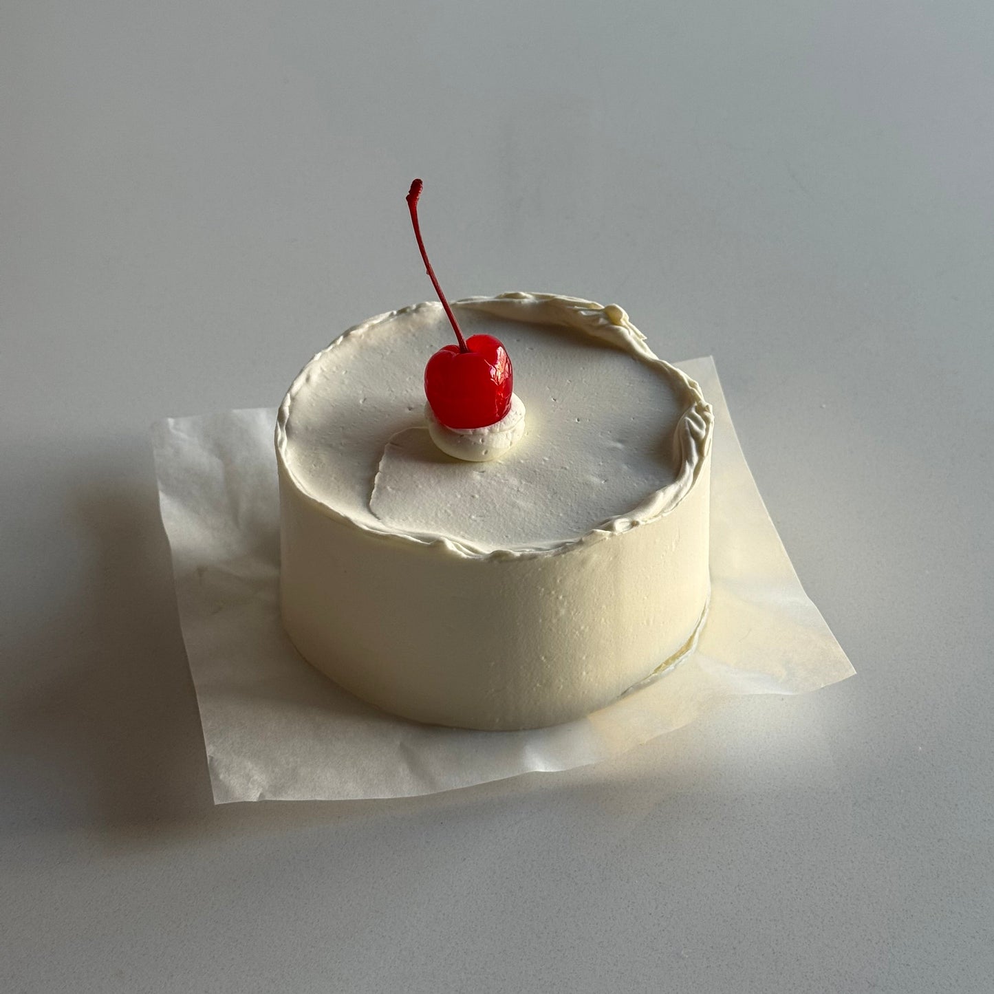 Small cake with a cherry on top attached to a wall