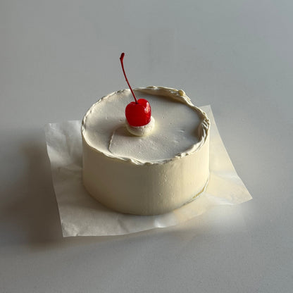 Small cake with a cherry on top attached to a wall