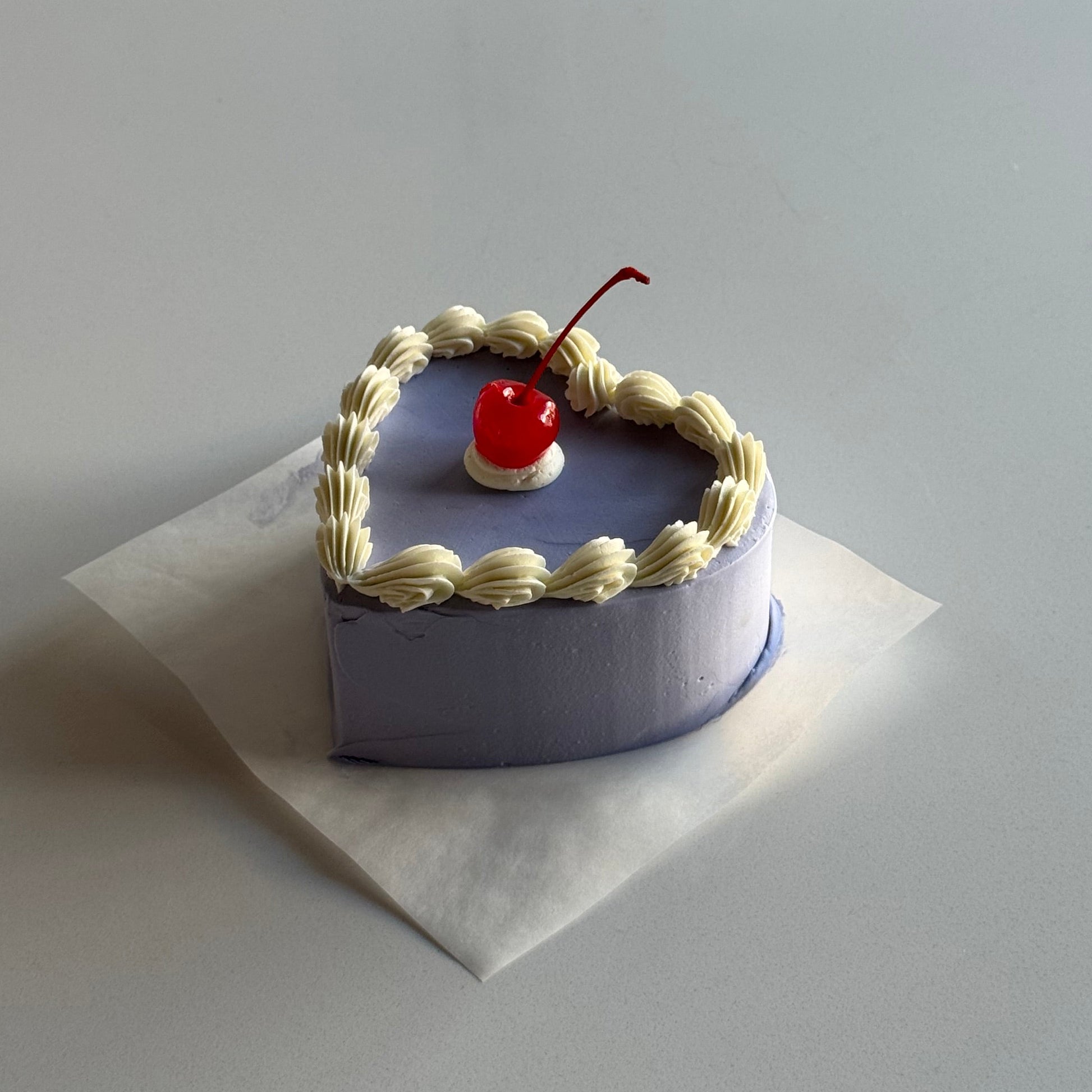 Small decorative heart-shaped box with a red cherry on top, placed on a white card.