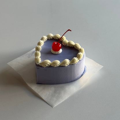 Small decorative heart-shaped box with a red cherry on top, placed on a white card.