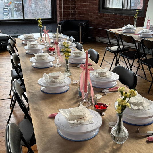 Table set up with turntables, cakes, supplies and decor for a cake & sip event in Montreal